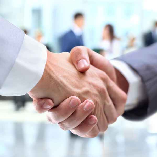 A close-up of a handshake between two business professionals in a bright corporate setting.