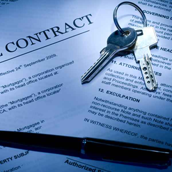 A real estate contract document with a set of keys and a pen placed on top.