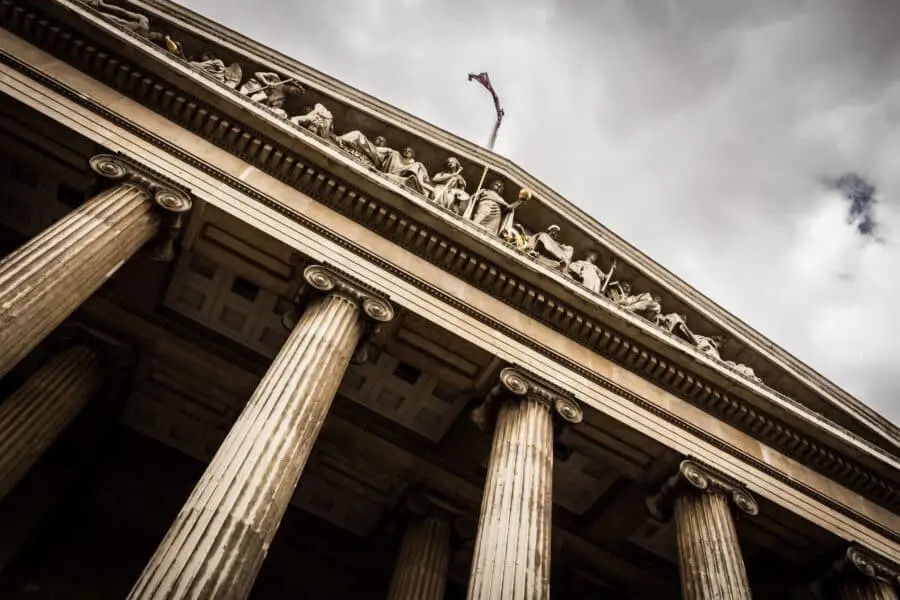 A low-angle shot of a grand courthouse with columns and intricate sculptures.