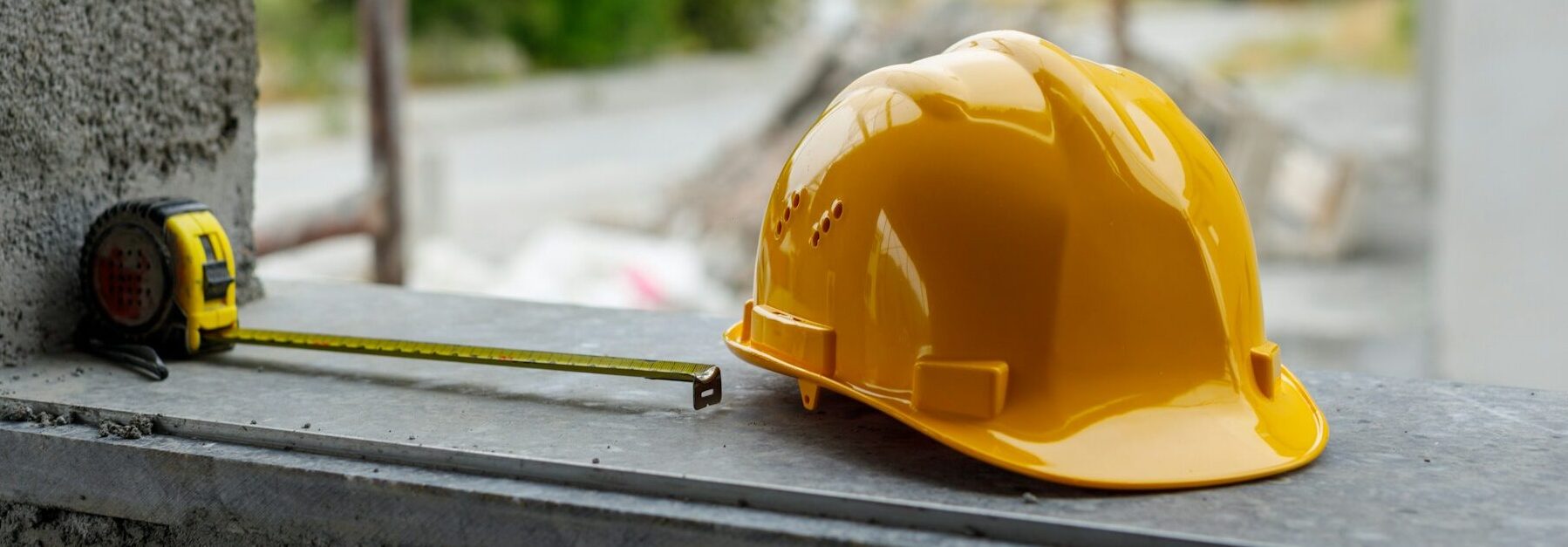 Tape measure and yellow hard hat sitting on a ledge